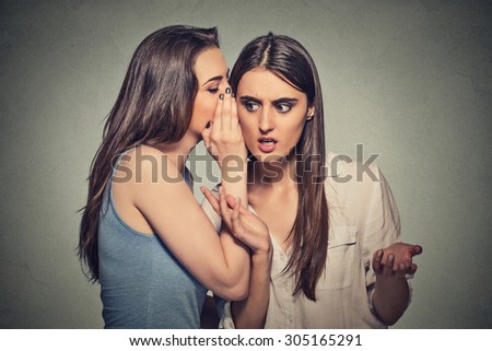 Girl whispering into woman ear telling her something funny and shocking secret. Human communication emotions facial expression feelings