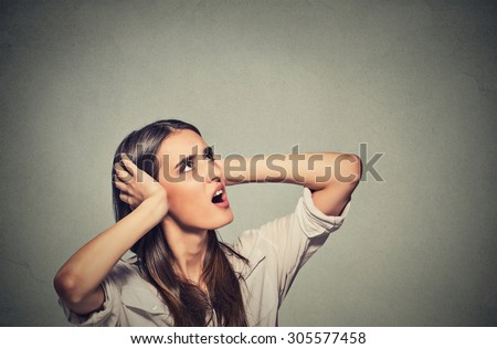 Portrait young annoyed, unhappy, stressed woman covering her ears, looking up, to say, stop making loud noise, giving me headache isolated grey background with copy space. Negative emotion reaction