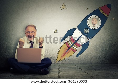 Excited senior man with high risky goals targets working on laptop computer on a starry spaceship wall background. Successful adventure dream concept