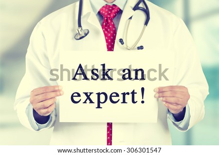 Closeup doctor hands holding white card sign with ask an expert text message isolated on hospital clinic office background. Retro instagram style filter image