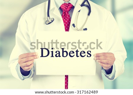Closeup doctor hands holding white card sign with diabetes text isolated on hospital clinic office background. Retro instagram style filter image. Healthcare concept