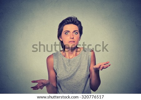 Portrait dumb looking woman arms out shrugs shoulders who cares so what I don\'t know isolated on gray wall background. Negative human emotion, facial expression body language life perception attitude