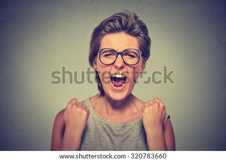 Angry young woman with glasses screaming fists up in air