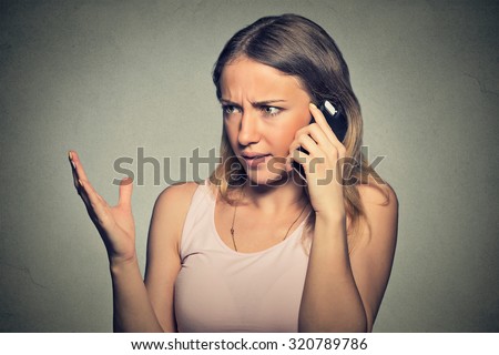 Closeup portrait upset angry skeptical, unhappy, serious woman talking on mobile phone isolated on gray wall background. Negative human emotion facial expression feeling, life reaction. Bad news