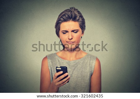 Closeup portrait upset sad skeptical unhappy serious woman talking texting on mobile phone displeased with conversation isolated on gray background. Negative human emotion face expression feeling