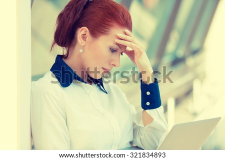 Side profile portrait stressed sad young woman with laptop standing in corporate office. City urban business life style stress
