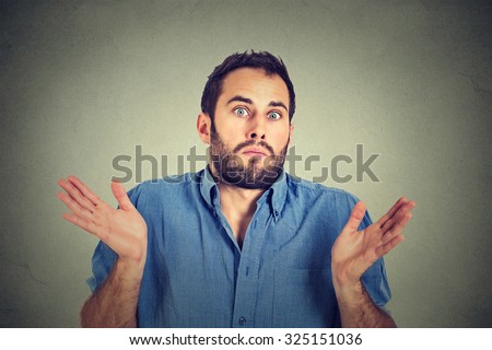 Closeup portrait young man shrugging shoulders who cares so what I don\'t know gesture isolated on grey wall background. Body language