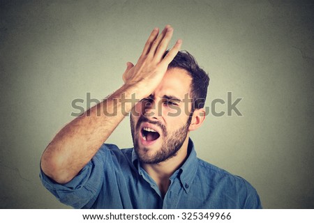 Regrets wrong doing.. Closeup portrait silly young man, slapping hand on head having a duh moment isolated on gray background. Negative human emotion facial expression feeling, body language, reaction