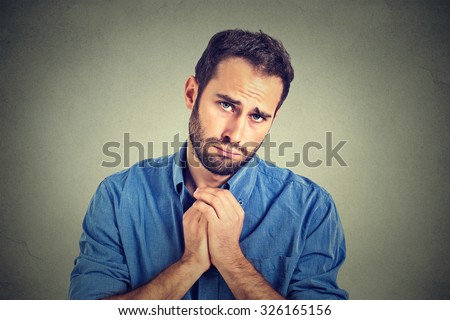 Closeup portrait of desperate young man showing clasped hands, pretty please with sugar on top isolated on gray wall background. Human emotion facial expression feelings, body language