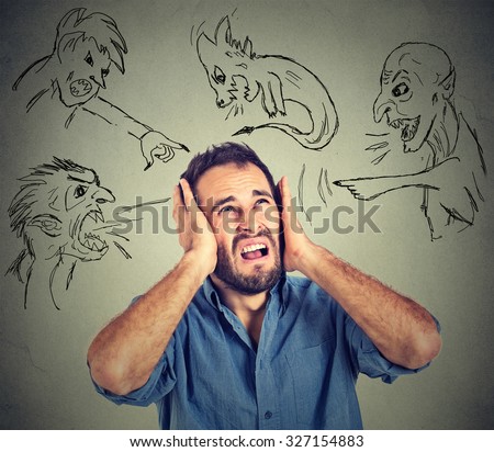 Stressed young man covers his ears with his hands evil guys pointing fingers at him blaming