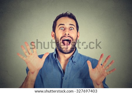 Happy young man going crazy screaming super excited isolated on gray wall background