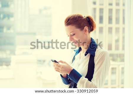 Side profile portrait beautiful young business woman texting on her smart phone isolated on acuity urban background