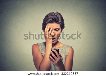 Upset stressed looking woman holding cellphone disgusted shocked with message she received isolated grey background. Human face expression emotion feeling reaction life perception body language
