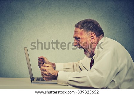 Angry furious senior business man working on computer, screaming. Negative human emotion facial expression feeling aggression anger management issues concept. Side profile guy having nervous breakdown