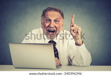Portrait excited senior man using laptop computer has an idea isolated on gray wall background