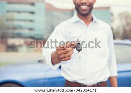 Happy smiling man holding car keys offering new blue car on background