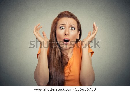Portrait frightened shocked scared woman looking at camera isolated on gray wall background. Human emotion facial expression body language unexpected reaction