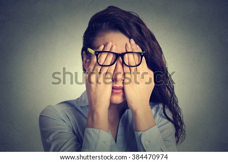 Closeup portrait young woman in glasses covering face eyes using her both hands isolated on gray wall background