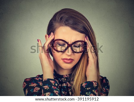 Closeup portrait sad young woman in glasses with worried stressed face expression isolated on gray wall background. Obsessive compulsive, adhd, anxiety disorder. Vision strain problems concept