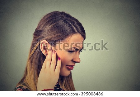 Tinnitus. Closeup side profile sick young woman having ear pain touching her painful head isolated on gray background