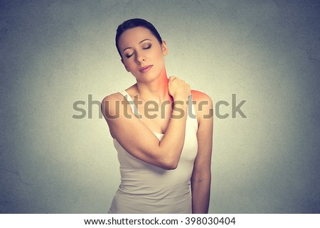 pain. Woman with painful neck shoulder colored in red isolated on gray wall background