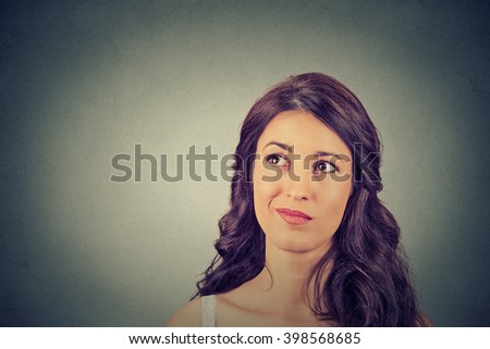 Closeup funny confused skeptical woman thinking planning looking up isolated on gray wall background copy space above head. Human face expression emotion feeling body language, perception reaction