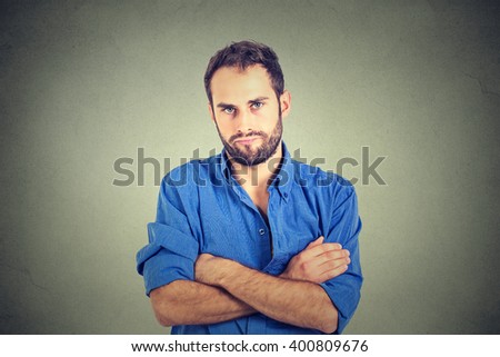 Closeup portrait of angry grumpy young man looking very displeased isolated on gray wall background. Negative human emotions facial expression feelings attitude