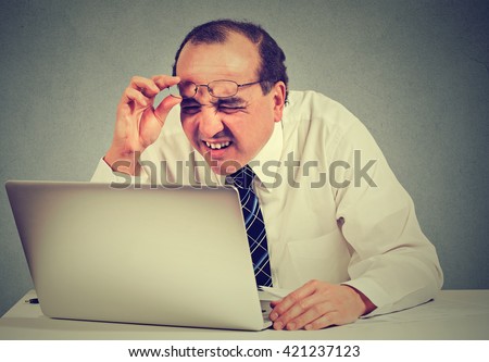 Closeup portrait middle aged business man with glasses having eyesight problems confused with laptop software isolated on gray background. Age related changes. Human face expression