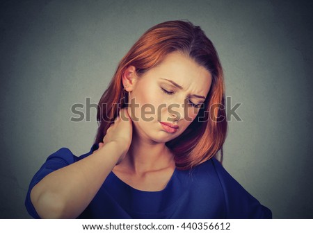 Back and spine disease. Closeup portrait tired woman massaging her painful neck isolated on gray wall background. Human face expression. Chronic fatigue disease