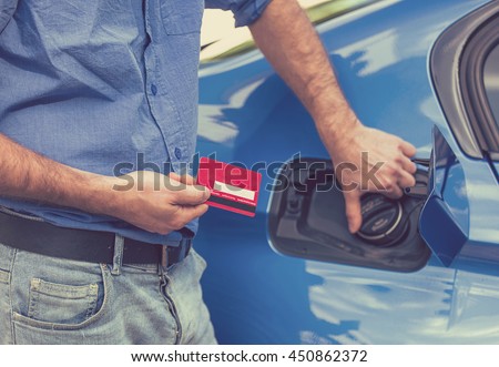 Man with credit card opening fuel tank of his new car