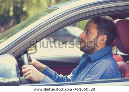 scared funny looking young man driver in the car. Human emotion face expression. Side window view of inexperienced anxious motorist