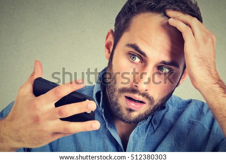 Preoccupied shocked man feeling head, surprised he is losing hair, receding hairline, bad news isolated on gray background. Negative facial expressions, emotion