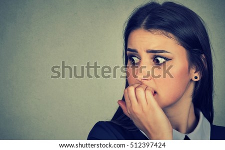 Closeup portrait young unsure hesitant nervous woman biting her fingernails craving for something or anxious isolated on gray wall background. Negative human emotions facial expression feeling