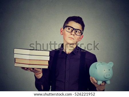 Student loan concept. Young man with stack pile of books and piggy bank full of debt rethinking  future career path