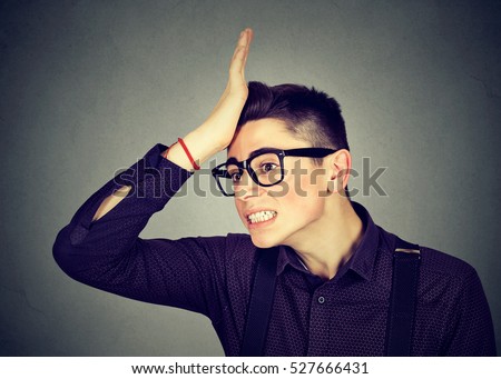 Regrets wrong doing. Silly young man, slapping hand on head having duh moment isolated on gray background. Negative human emotion facial expression feeling, body language, reaction