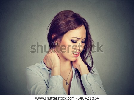 Back and spine disease. Closeup portrait tired woman massaging her painful neck isolated on gray wall background. Human face expression. Chronic fatigue