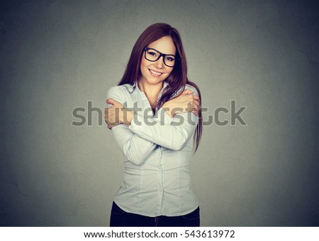 Smiling woman holding hugging herself isolated gray wall background. Positive human emotion, facial expression. Love yourself concept
