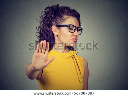 Portrait young angry woman with bad attitude giving talk to hand gesture with palm outward isolated on gray background. Negative human emotion face expression feeling body language