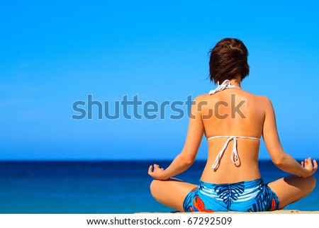 Closeup portrait, back side view of young beautiful woman meditating in zen mode on beach, siting on sand in front of pacific ocean. Healthy life style, stress relief techniques. Vacation, travel