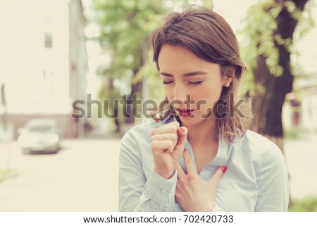 Young woman having asthma attack or choking can\'t breath suffering from respiration problems standing outdoors on a urban street
