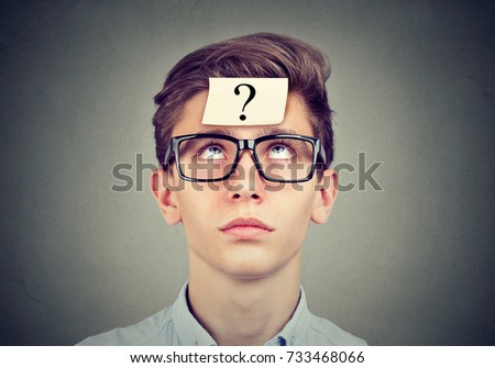 thinking man with question mark looking up on gray wall background