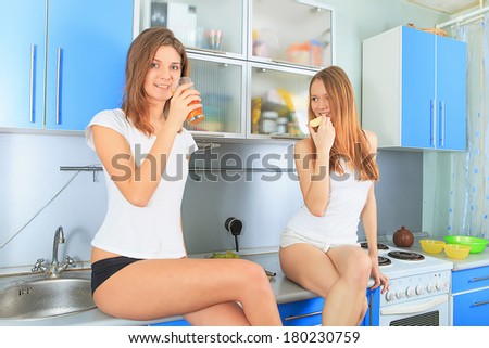 Two girl friends talk in kitchen