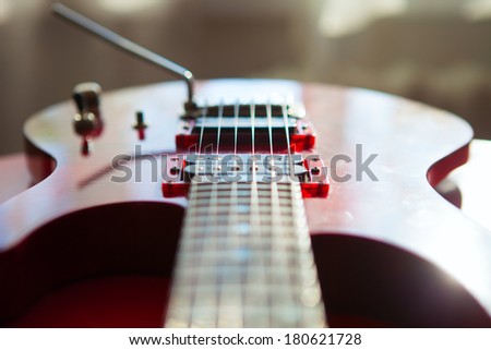Red electric guitar laying on a red velvet.