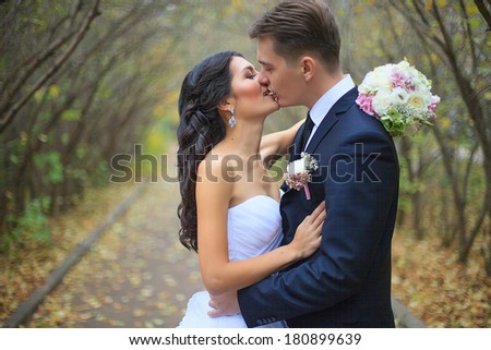 Lovely couple in love kissing each other on the day of the wedding they are even standing in the park outdoors - copyspace