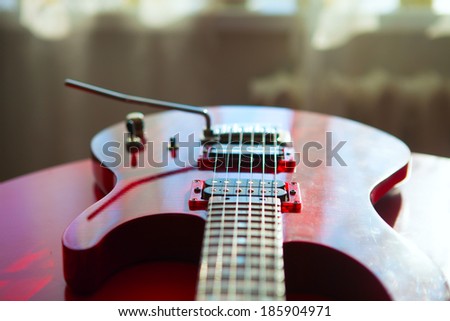 Red electric guitar laying on a red velvet.