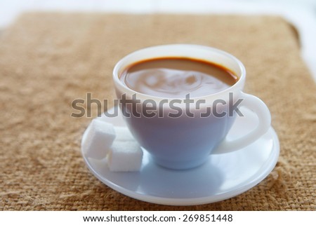 White coffee cup with rich coffee  on a textile background
