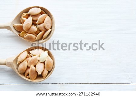 Pumpkin seeds in spoon on white wooden table with clipping path