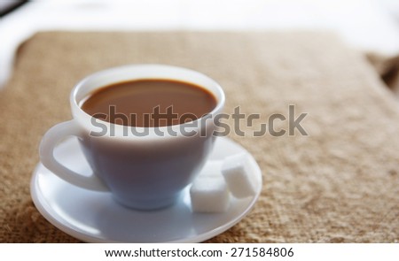 White coffee cup with rich coffee  on a textile background