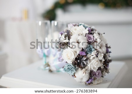 Winter wedding bouquet. Wedding bouquet of flowers lying on a chair near two wedding glasses.