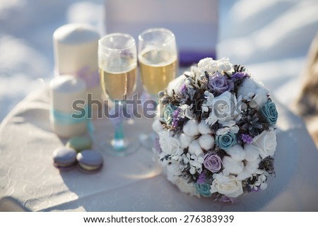 Winter wedding bouquet. Wedding bouquet of flowers lying on a chair near two wedding glasses and candle.